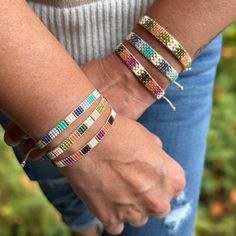 a woman wearing bracelets with multi colored beads on her wrist and holding the other hand