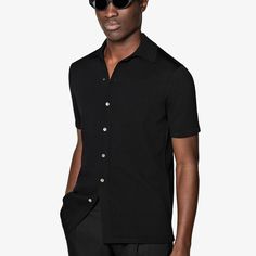 A perfect way to elevate any casual look, this black short-sleeve polo cardigan features a classic polo collar, a seven-button closure, and a slim, tapered silhouette for a sleek aesthetic. Black Polo Shirt With Button Closure, Black Short Sleeve Polo Sweater For Work, Classic Black Polo Shirt With Collared Neckline, Black Polo Shirt With Placket, Modern Black Polo Shirt With Collared Neckline, Black Polo Collar Sweater For Work, Black Polo Shirt With Seamless Collar For Work, Fitted Polo Sweater With Button Closure, Classic Fitted Polo Sweater With Buttons