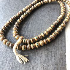 Unique and powerful Nepali Yak Bone Mala. Each bead has bras and small stone details. A unique unisex piece that will be perfect for your day by day outfits. The Mala is 40.6cm- 16 inch long A most have addition to your jewelry collection. Enjoy Con salud Wooden Beads Amulet Jewelry For Festival, Amulet Style Jewelry With Wooden Beads For Festival, Festival Amulet Style Jewelry With Wooden Beads, Meditation Jewelry With Wooden Round Beads, Wooden Beads Amulet Necklace As A Gift, Wooden Beads Amulet Necklace For Gift, Amulet Style Wooden Beaded Necklace For Gifts, Amulet Style Wooden Beaded Necklaces For Gifts, Amulet Style Wooden Beaded Necklace As Gift