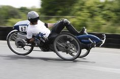 a man riding on the back of a motorcycle down a road