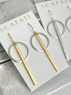 "Very simple textured hoops enhanced with a textured bar. The hoops are rack plated with a silver alloy and 18 K gold over brass. Rack plating means they are hand hung so there is optimal coverage and the plating has a glossy finish. Two finish combinations are available: Silver - 2 1/2\" in length Silver and Gold 2 1/2\" in length The wires are plated with 16 K Gold and a silver alloy over brass and come with rubber back stoppers. All metals are lead safe." Textured Drop Earrings For Gifts, Modern Hammered Linear Earrings As Gift, Textured Metal Hoop Earrings For Gift, Modern Hammered Hoop Earrings As Gift, Modern Hammered Hoop Earrings For Gift, Modern Textured Jewelry For Gifts, Modern Textured Jewelry As Gift, Modern Hammered Hoop Earrings Gift, Modern Hammered Linear Earrings For Gift