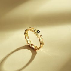 a gold ring sitting on top of a white table next to a shadow from the sun