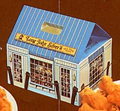 two plates with fried chicken on them and a small blue building in the middle that says happy john's