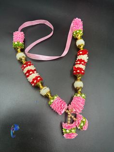 a pink and green beaded necklace on a black table next to a pair of scissors