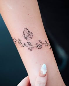 a woman's arm with a butterfly and leaves tattoo on the left side of her arm