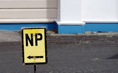 a yellow street sign sitting on the side of a road next to a blue building