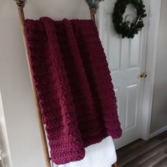 a red blanket sitting on top of a wooden chair next to a white front door