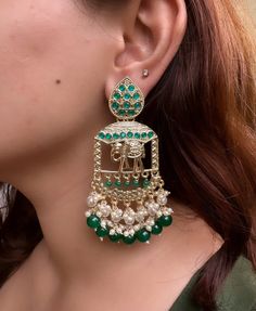 Embrace the regal allure of Indian tradition with our exquisite Golden Emerald Kundan Indian Earrings, intricately designed in the shape of majestic elephants. These earrings embody the perfect blend of elegance, cultural richness, and timeless beauty, making them a captivating addition to your jewelry collection. Crafted with meticulous artistry, these earrings feature radiant golden tones that gracefully enhance the intricate detailing of the elephant design. The mesmerizing Kundan setting showcases vibrant emerald gemstones, adding a touch of royal splendor and captivating allure to these unique earrings. Each piece is meticulously handcrafted by skilled artisans, ensuring that every delicate element of the elephant motif is brought to life with utmost precision. The rich heritage of In Traditional Bridal Earrings With Intricate Design For Navratri, Traditional Peacock Design Danglers For Party, Traditional Peacock Danglers For Party, Gold Bollywood Jhumkas With Motifs, Gold Chandbalis With Motifs For Diwali, Festive Chandbalis With Motifs, Green Chandbali Chandelier Earrings With Intricate Design, Traditional Meenakari Chandelier Earrings For Festive Occasions, Temple Jewelry Style Danglers For Eid With Intricate Design