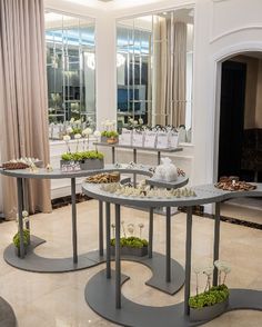 a room filled with lots of tables covered in plants and vases next to windows