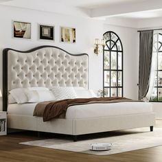 a white bed sitting in a bedroom on top of a hard wood floor next to a window