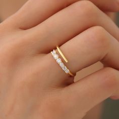 a woman's hand wearing a gold ring with three stones on the middle finger