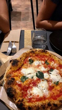 a pizza sitting on top of a table next to a fork and glass filled with water