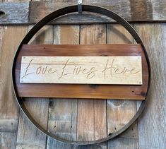 a wooden sign that says love lives here hanging on the side of a wood wall