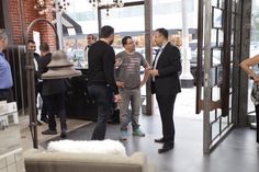 a group of people standing in front of a store door talking to each other and one man wearing a suit