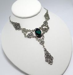 This is a new handmade necklace. It is made with antiqued silver plated filigrees, accented with a high quality EMERALD GREEN glass rhinestone. Decorated portion is 6" wide and 3 1/4" tall in the center. Necklace is adjustable 15-18" with a lobster clasp and chain extender. If you would like a different length, please send us a message. Gothic Metal Jewelry With Filigree, Gothic Antique Silver Jewelry With Intricate Design, Gothic Sterling Silver Jewelry With Intricate Design, Gothic Filigree Metal Jewelry, Antique Silver Victorian Metal Necklace, Victorian Antique Silver Necklace, Victorian Antique Silver Metal Necklace, Gothic Metal Necklace With Intricate Design, Antique Silver Gothic Jewelry With Filigree