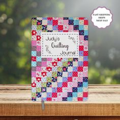 a colorful quilt book sitting on top of a wooden table