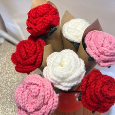 several crocheted flowers in a vase on a table