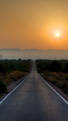 the sun is setting on an empty road in the middle of nowhere with no traffic