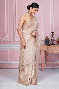 Flaunt your elegant style on festive occasions in this stunning beige embroidered tissue silk saree. It comes with a matching blouse piece. Disclaimer: The shown stitched blouse on the model is for display purpose only. The saree comes with a matching blouse piece and finished with fall and piko. Gold Tussar Silk Saree For Reception, Beige Zari Work Pre-draped Saree For Wedding, Beige Pre-draped Saree With Zari Work For Wedding, Wedding Beige Pre-draped Saree In Traditional Style, Beige Semi-stitched Anarkali Saree, Beige Wedding Pre-draped Saree, Cream Tissue Silk Traditional Wear For Eid, Semi-stitched Beige Saree For Eid, Beige Saree With Intricate Embroidery