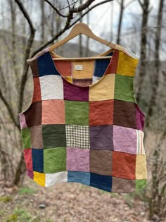 a multicolored patchwork shirt hanging on a clothesline in the woods with trees