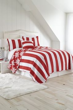 red and white striped bedding in a room with hardwood flooring, windows, and rugs