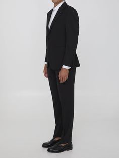 This two-piece suit is made of black virgin wool and includes a single-breasted jacket with peaked lapels, a brooch on the lapel, a front button closure, two front welt pockets, a welt pocket on the chest, and buttoned cuffs. The straight-leg trousers feature a zip, button, and hook-and-eye closure, as well as two side welt pockets and two rear buttoned welt pockets. Size nationality: Italy Buttoned cuffs Peaked lapels Button closure Front pockets Straight leg pants Rear pockets Regular fit Prod Tailored Elegant Formal Pantsuit, Elegant Tailored Pantsuit For Formal Occasions, Tailored Elegant Pantsuit For Formal Occasions, Luxury Lapel Collar Semi-formal Pantsuit, Luxury Semi-formal Pantsuit With Lapel Collar, Black Suits With Lapel Collar For Evening, Black Tie Tuxedo Blazer With Hidden Button Closure, Tuxedo Blazer With Hidden Button Closure For Black Tie, Elegant Single Breasted Formal Pantsuit