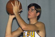 a young man holding a basketball in his right hand and looking up at the ball