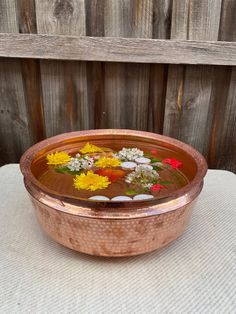 a copper bowl filled with flowers on top of a table