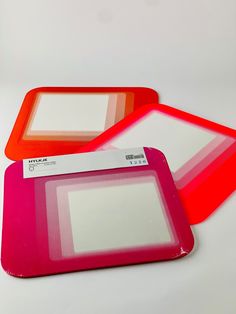 two red and pink trays sitting next to each other on a white table top