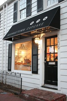 a store front with black shutters on the windows and an awning that says georgetown cupcake