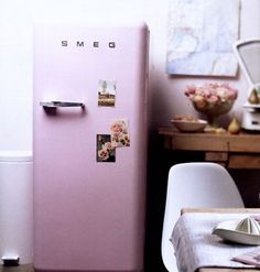 a pink refrigerator sitting in the middle of a kitchen next to a table and chairs