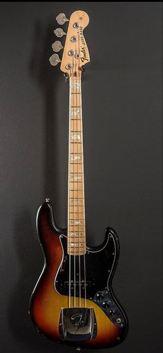 an electric bass guitar hanging on the wall