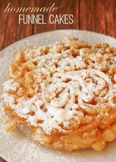 homemade funnel cakes on a white plate with powdered sugar and cinnamon sprinkles