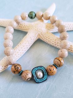 Get those sandy vibes flowing with our Beachy Bracelets, featuring natural stones, patina green accents, pearls, and cute ocean-inspired charms. Our Mykonos Collection would not be complete without some versatile, easy-to-use stretch bracelets. Wear one alone or stack a few for a bold BoHo look. Each bracelet features antiqued patina charms and spacers made in Greece, where the art of metal finishing was popular already thousands of years ago. Pearls, stingrays, shells, and other fun shapes ador Cheap Ocean-inspired Beaded Bracelet, Everyday Bohemian Turquoise Stretch Bracelet, Earthy Natural Stone Beaded Bracelets For Beach, Adjustable Turquoise Bohemian Pearl Bracelet, Bohemian Beige Stretch Bracelet As Gift, Bohemian Pearl Bracelet For Beach With Round Beads, Bohemian Turquoise Pearl Bracelet With Round Beads, Bohemian Pearl Bracelet With Round Beads For Beach, Handmade Bohemian Sand-colored Jewelry