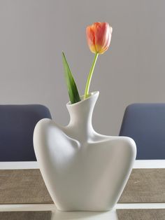 a white vase with a single tulip in it sitting on top of a table