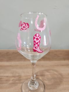 a wine glass with pink and white designs on the bottom is sitting on a wooden table