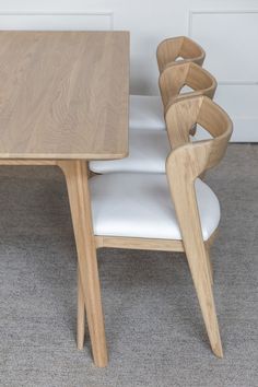 a wooden table sitting next to a white chair on top of a carpeted floor