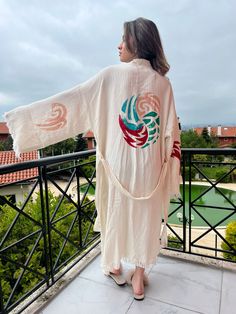 "Beautiful handmade white kimono robe with colorful four elements ethnic design, designed with muslin cotton fabric, it flows as you move for comfortable wear. Beach cover-up, nightwear, and a white kimono with fire, earth, air, and water elements. This is a lovely, good-quality kimono, with traditional breathable kimono sleeves.        A belt that ties around the waist. Great to wear around the house, on beaches, or to dress up with some jeans & a T-shirt, covering up on the beach with a swimsuit.         We love kimonos as they are so versatile. They also make really special & unique birthday, valentines Day, Christmas gifts, and Mother's Day gifts. The perfect combination of comfort and style, this kimono is a great addition to your new season wardrobe.    Cotton Fabric and Handmade White Hippie Kimono For Spring, White Bohemian Kimono For Beach, Cream Kimono With Kimono Sleeves For Vacation, Traditional White Robe For Spring, White Hippie Kimono For Beach, Cream Beach Kimono With Kimono Sleeves, Traditional Beige Kimono For Vacation, Long Cream Kimono For Vacation, Traditional Long Sleeve Kimono For Beach