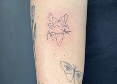 a woman's arm with tattoos on it, including a butterfly and a cupcake