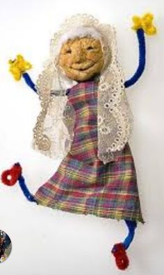 the doll is dressed in plaid and has a white veil over her head, holding two yellow flowers