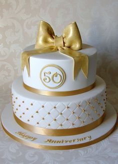 a three tiered cake with gold bows on top and the number thirty written on it