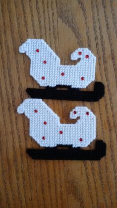 two pieces of beaded fabric sitting on top of a wooden table