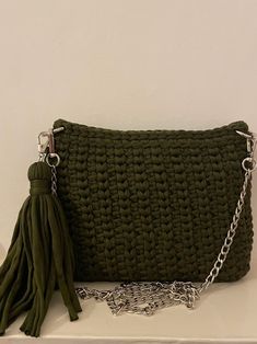 a green purse sitting on top of a white shelf next to a chain link bag