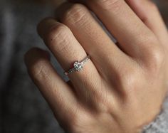 a woman's hand with a diamond ring on top of her finger, showing the band