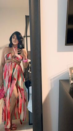 a woman in a colorful dress taking a selfie with her cell phone while standing in front of a mirror