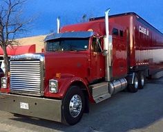 a red semi truck parked in front of a building