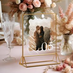 a table topped with a vase filled with flowers and a photo frame on top of it