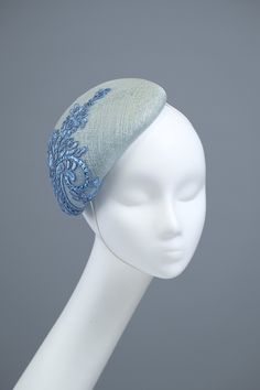 This stylish, elongated button-shape fascinator decorated with blue embroidery. The fascinator attaches with a millinery elastic and should be worn at the left side of your head. This headpiece is hand formed and sewed, making it an exclusive design. Blue Mini Hat Headband For Spring, Blue Headband For Spring Wedding, Blue Adjustable Headband Fascinator, Adjustable Blue Headband Fascinator, Blue Headband For Summer, Elegant Blue Mini Hat With Structured Crown, Blue Headband For Royal Ascot, Blue Sinamay Fascinator For Wedding, Blue Fitted Headband For Kentucky Derby