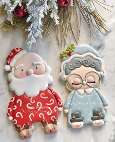 two decorated cookies sitting next to each other on top of a white countertop with christmas decorations