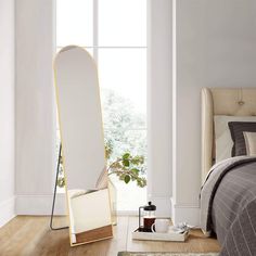 a bedroom with a bed, mirror and rug on the floor in front of it